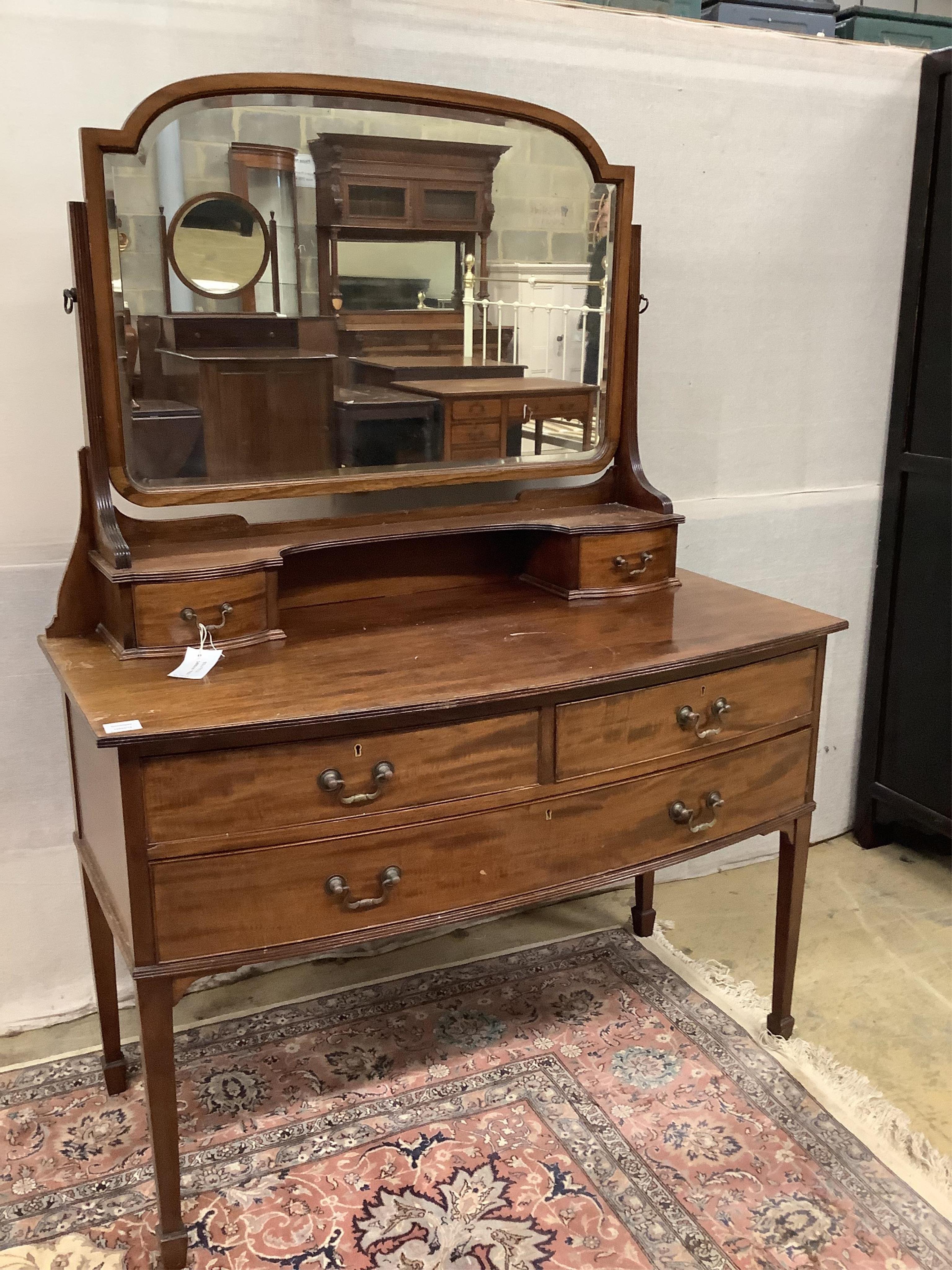 An early 20th century mahogany bowfront dressing table, fitted two short and one long drawer with brass loop handles and square tapered legs with spade feet, width 116cm, depth 57cm, height 156cm. Condition - fair